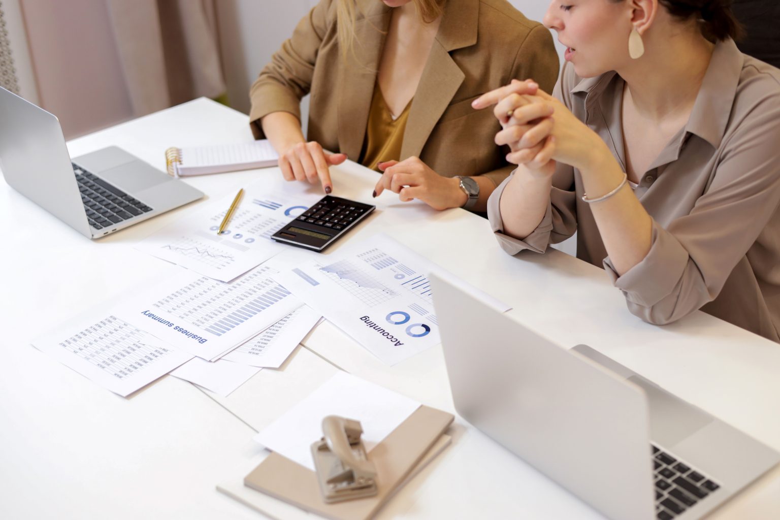 Collega’s bespreken financiële documenten bij hun laptops
