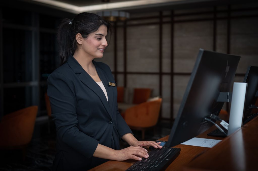 Hotelmedewerker werkt aan een computer bij de receptie