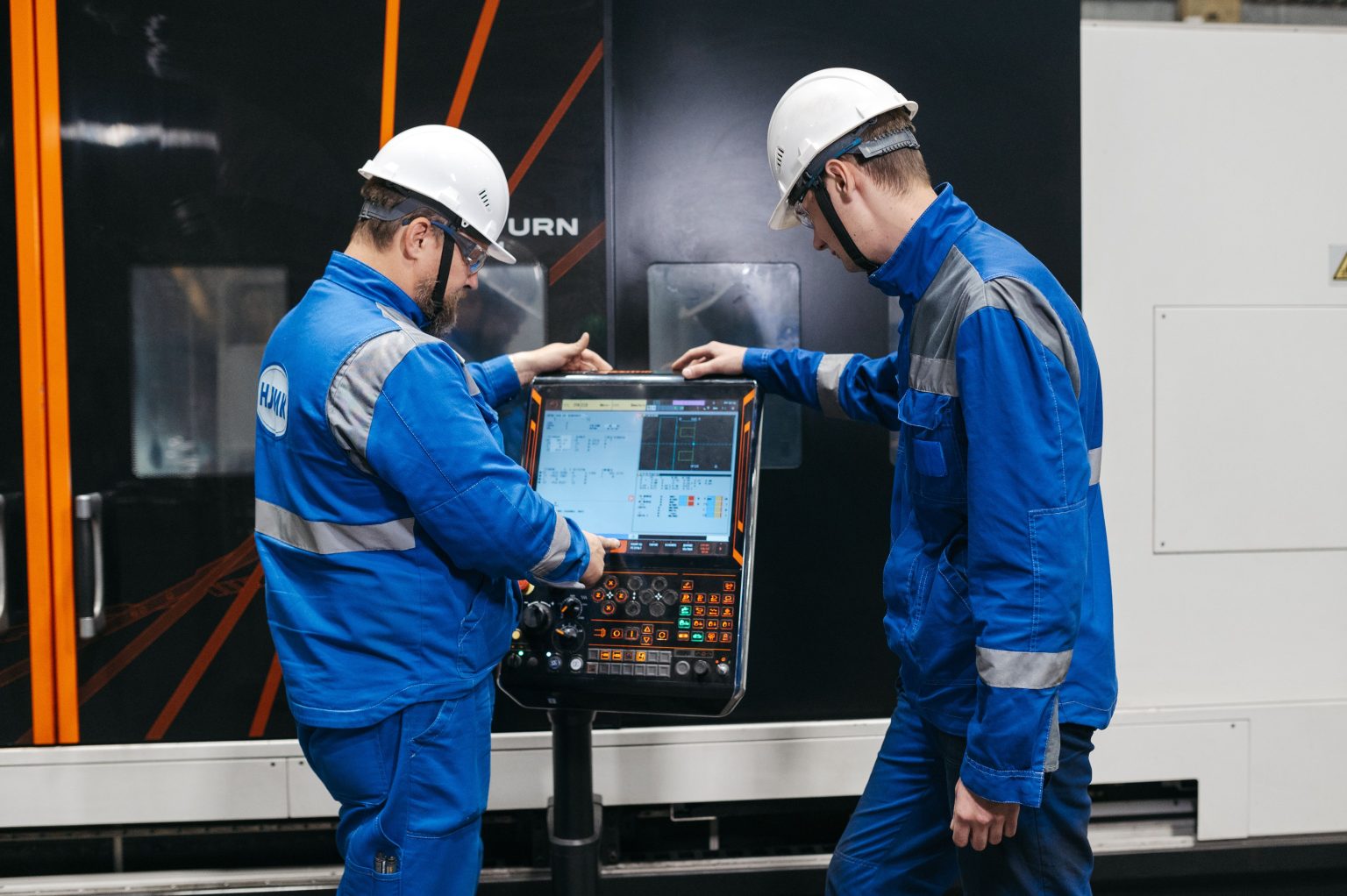Twee medewerkers bedienen een productiemachine via een digitaal scherm