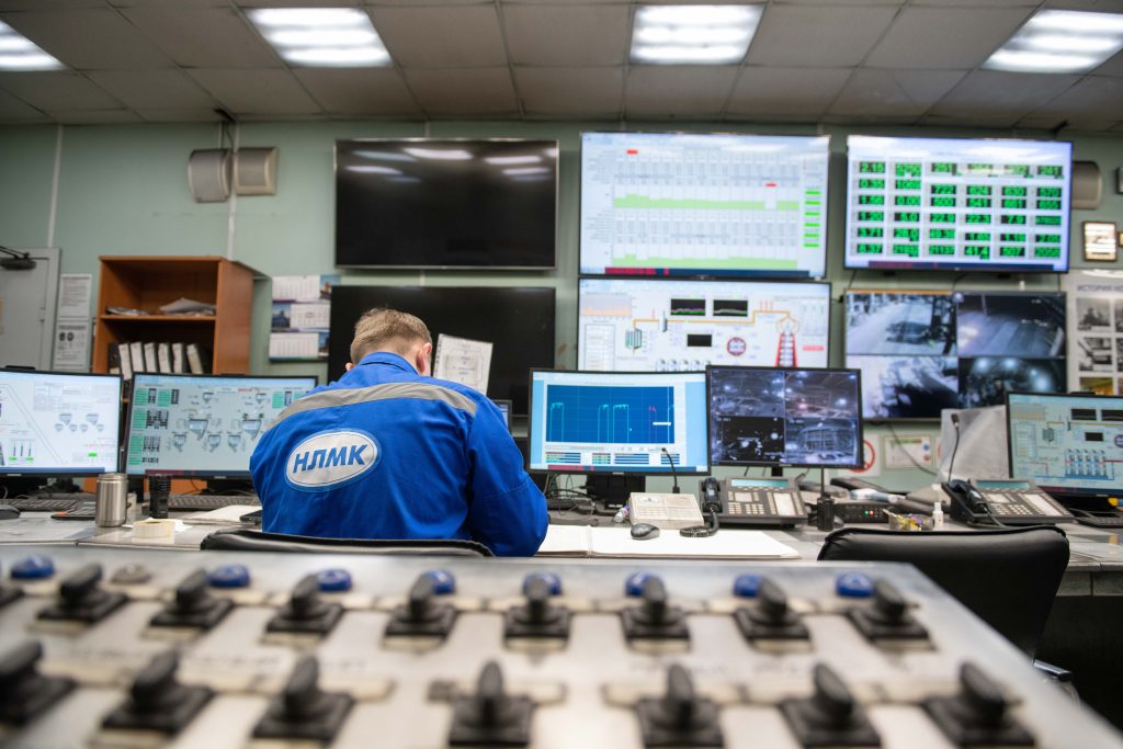 Medewerker werkt achter meerdere beeldschermen in een industriële controlekamer
