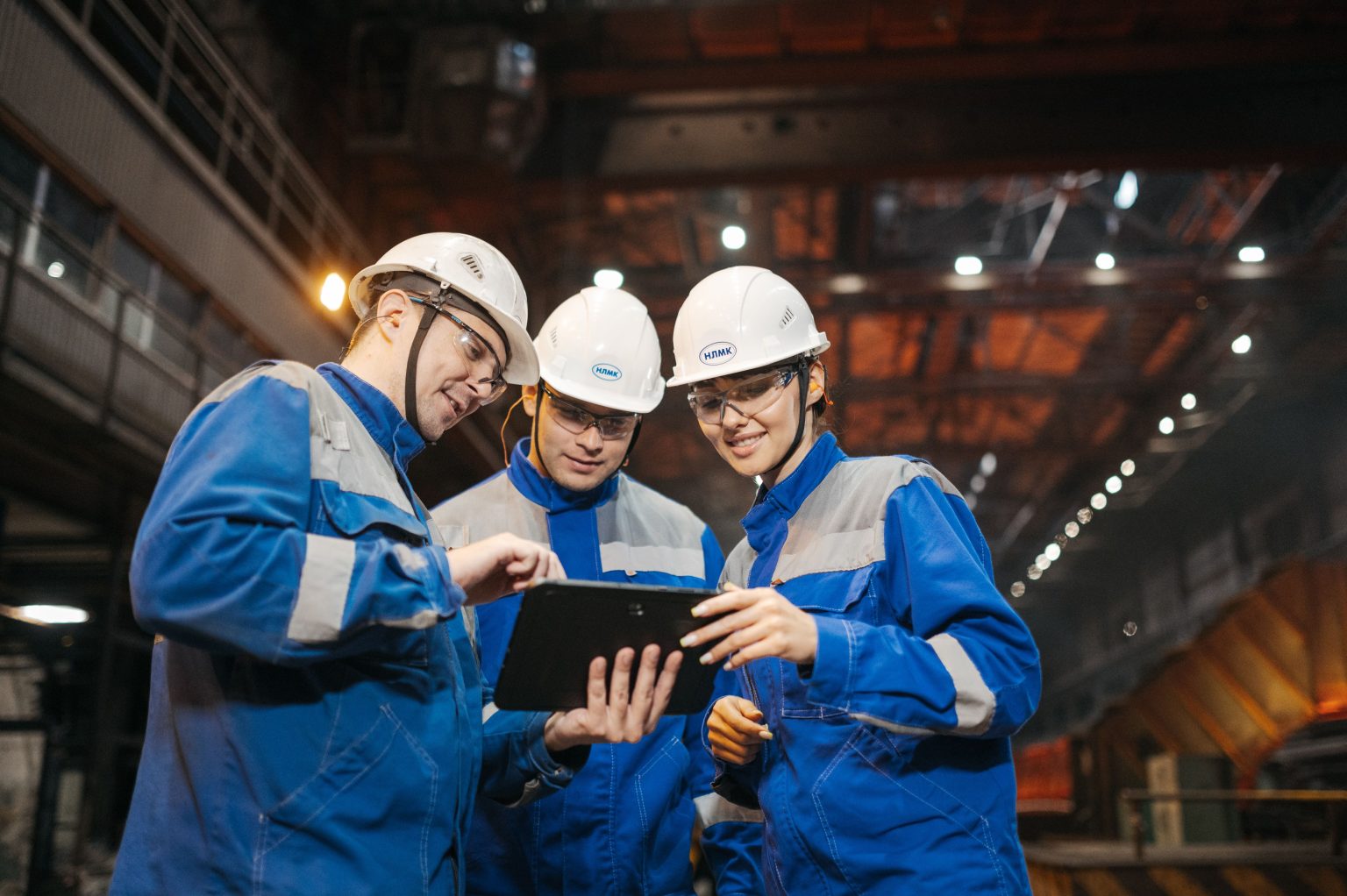 Drie technici in een bedrijfshal bekijken samen informatie op een tablet