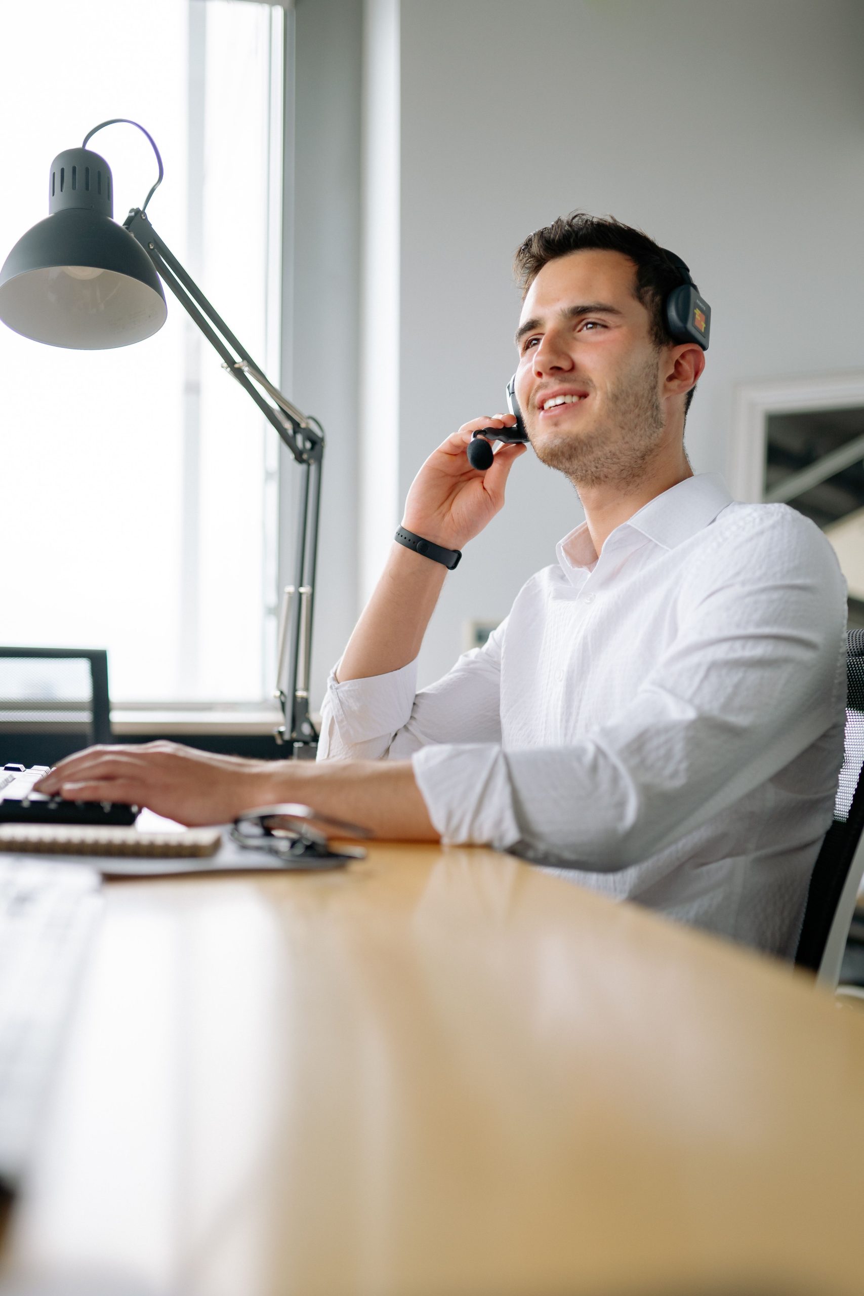 Medewerker belt met een headset aan zijn werkplek