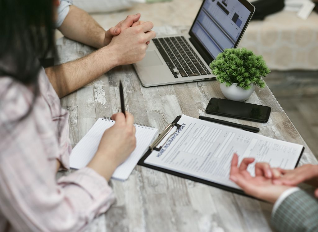Adviesgesprek aan tafel met een laptop en een verzekeringsdocument