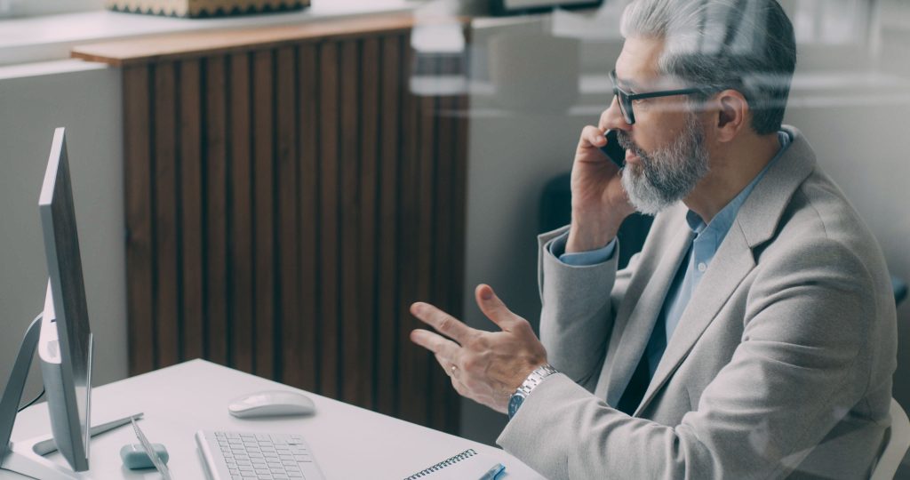 Zakelijke medewerker telefoneert bij een verzorgde computerwerkplek